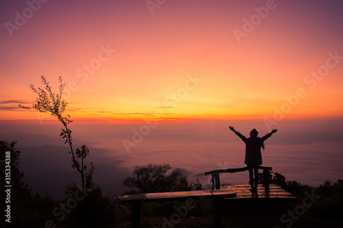 Silhouette of a girl in front of the sunset on the hill.