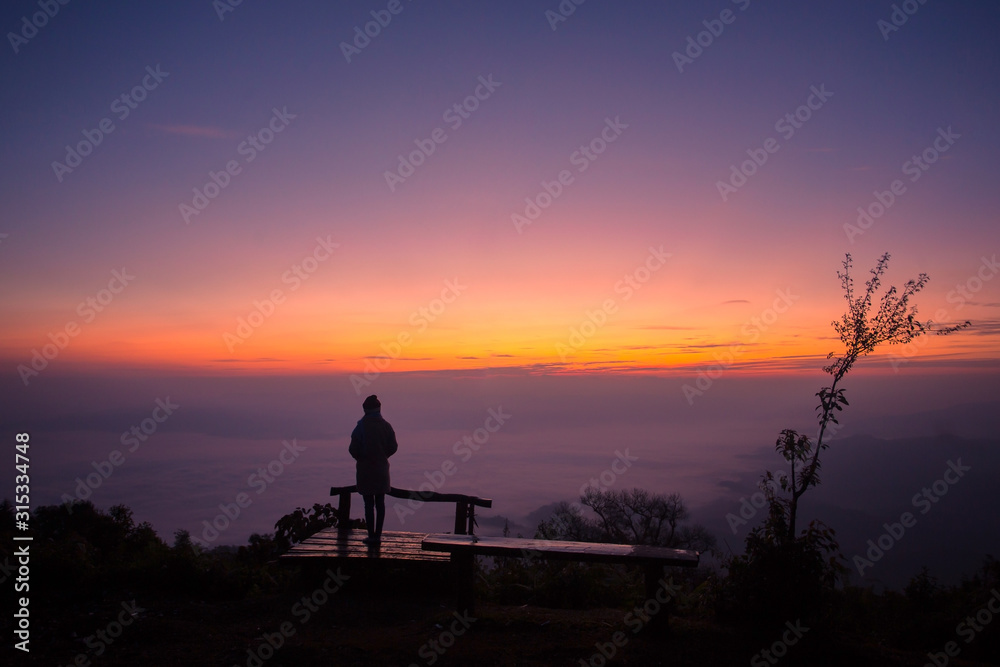 Silhouette of a girl  in front of the sunset on the hill.