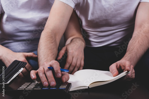 Young couple calculating their family budget sitting together on couch. Wife supports her husband in difficult times. Family financial crisis concept. photo