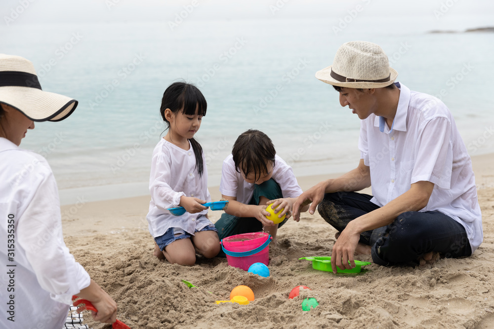 Happy Asian Family Four people On Summer Vacation playing toys on sand in the beach together In the morning time, sunrise. Holiday and Travel concept. Happy Asian Family Four people On Summer Vacation playing toys on sand in the beach together In the morning time, sunrise. Holiday and Travel concept.