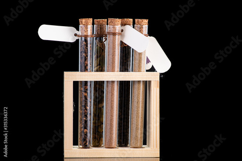 black pepper peas scattered next to the test tube and cork on a dark background