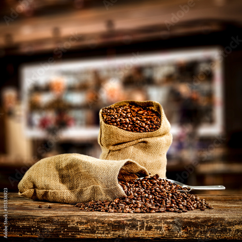 Wooden board of free space for your decoration and fresh coffee beans in brown sacks. 
