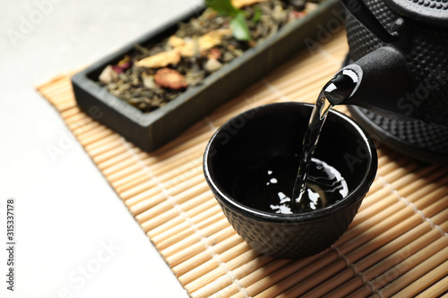 Pouring green tea into cup on table. Space for text