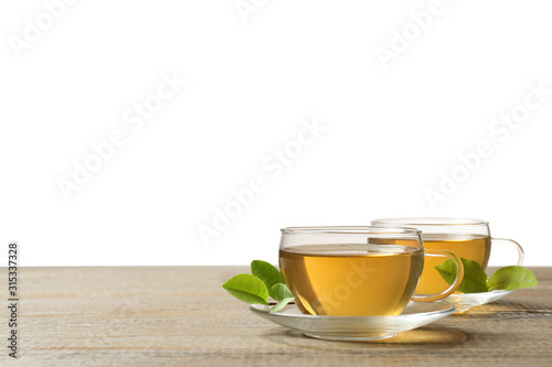 Cups of green tea and leaves on wooden table