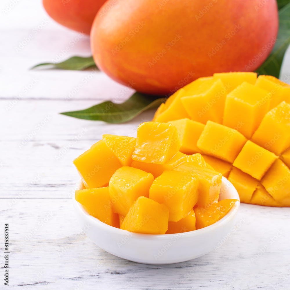 Fresh mango,beautiful chopped fruit with green leaves on bright wooden table background. Tropical fruit design concept, close up, copy space. Fresh mango,beautiful chopped fruit with green leaves on bright wooden table background. Tropical fruit design concept, close up, copy space.