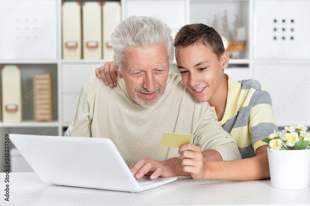 Boy and grandfather with a laptop at home shopping online Boy and grandfather with a laptop at home shopping online