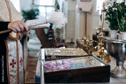 Принти на полотні Priest is sprinkling holy water on wedding rings at church