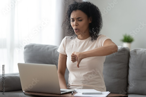Billede på lærred Dissatisfied african woman looking at computer screen showing thumbs down