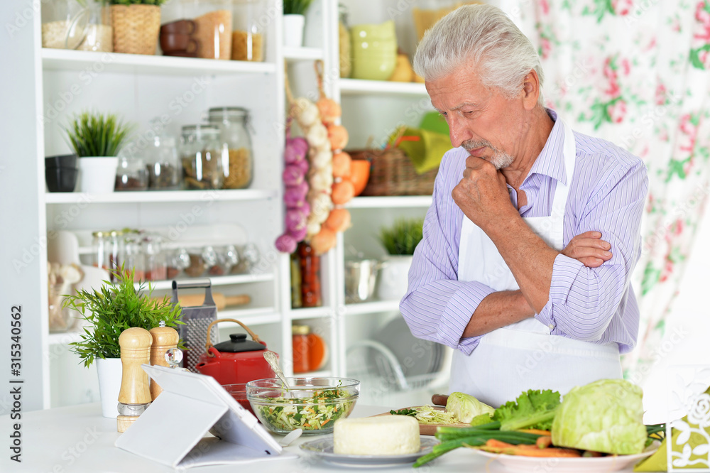 Portrait of senior man preparing dinner in kitchen Portrait of senior man preparing dinner in kitchen