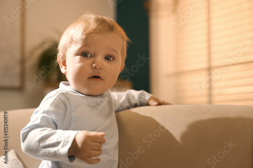 Cute little baby with on sofa indoors