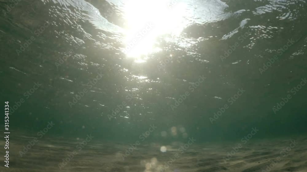 Underwater surface shot in the mediterranean sea. Beautiful lightrays piercing water.