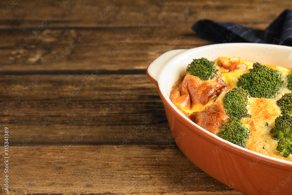 Tasty broccoli casserole in baking dish on wooden table. Space for text Tasty broccoli casserole in baking dish on wooden table. Space for text