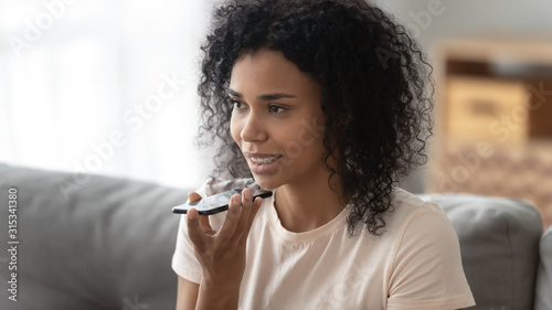 Fotografie African woman speaking using loudspeaker on mobile phone