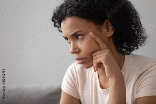 Closeup african pensive woman sit indoors feels discontented having problems