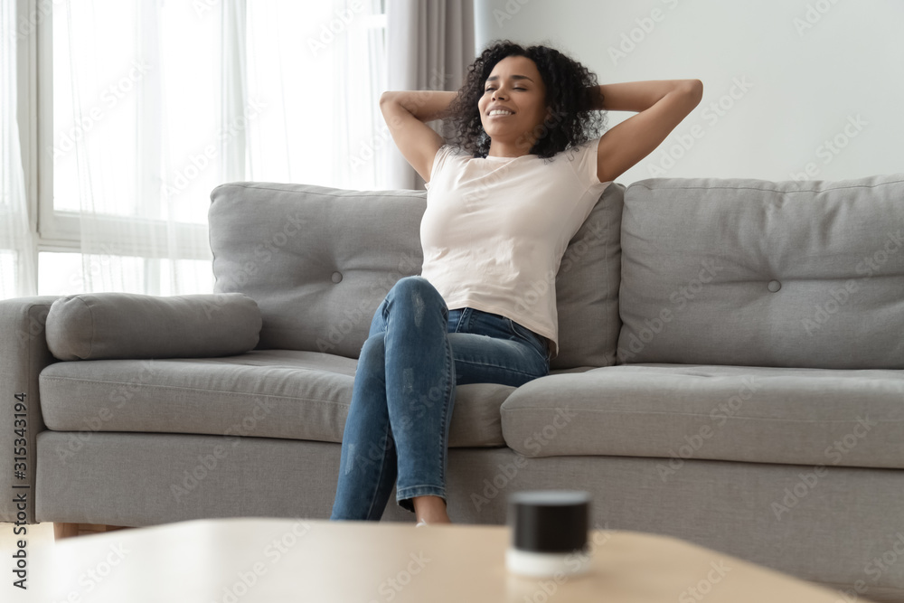 Serene african woman leaned on couch resting in living room Serene african woman leaned on couch resting in living room