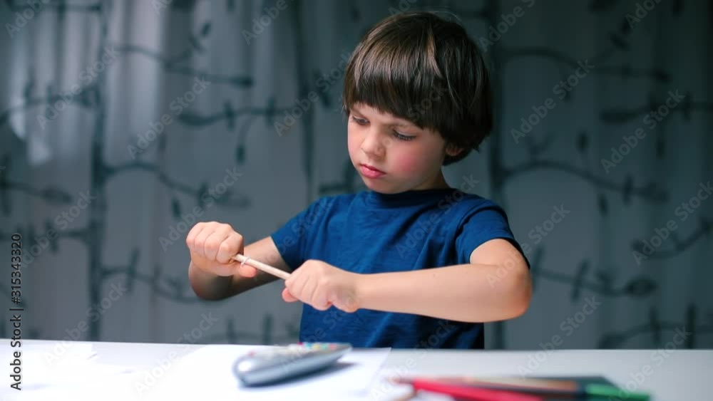 A child is played with a pencil while sitting at a table in school. A child is played with a pencil while sitting at a table in school.
