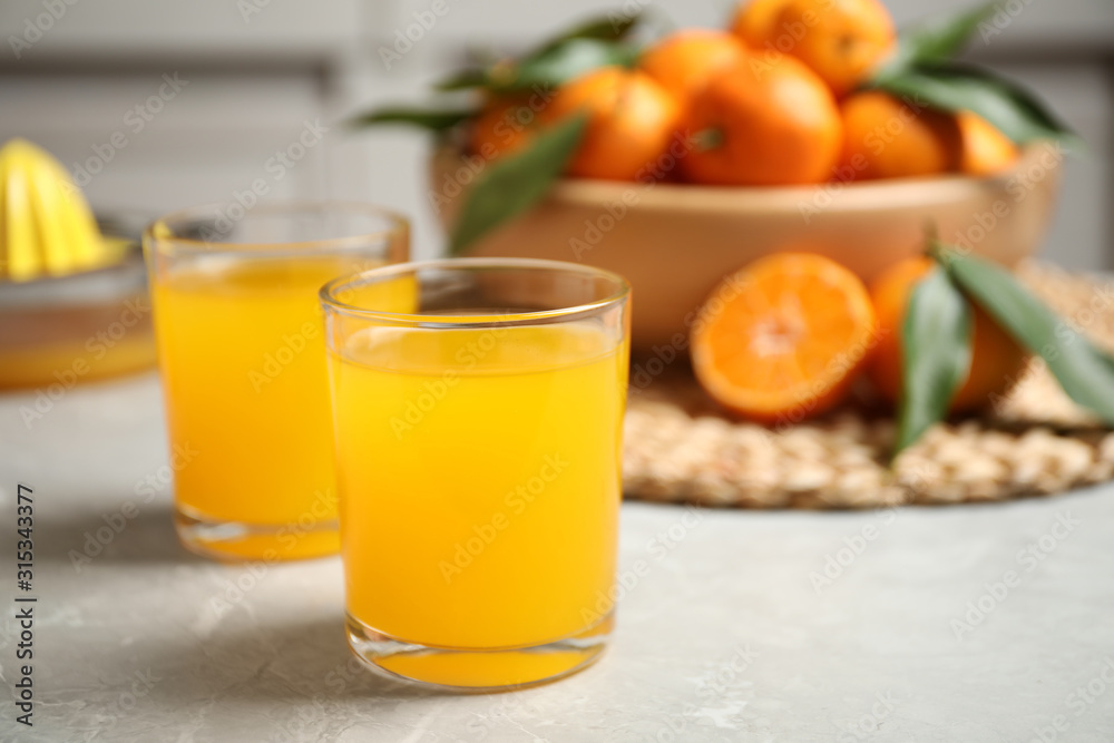 Glasses of fresh tangerine juice on marble table