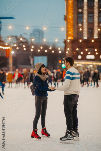 Young couple skates at the rink and holds hands.