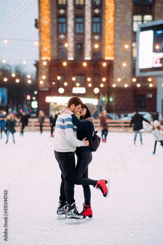 Young couple skates at the rink and embraces.