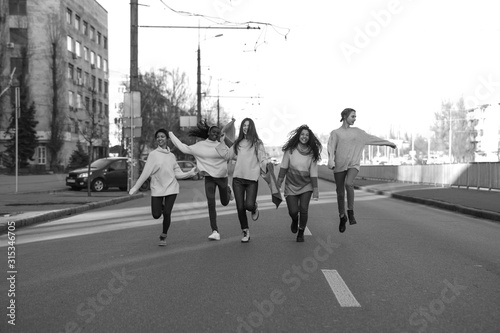 Fototapeta Naklejka Na Ścianę i Meble -  Multiracial group of friends runs and has a fun on city street.