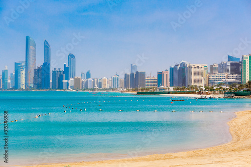Skyline view of Abu Dhabi panorama with sea, beach and skyscrapers. Sunny summer day in Abu Dhabi - famous tourist destination in UAE. Ideal place for luxury travel and rest