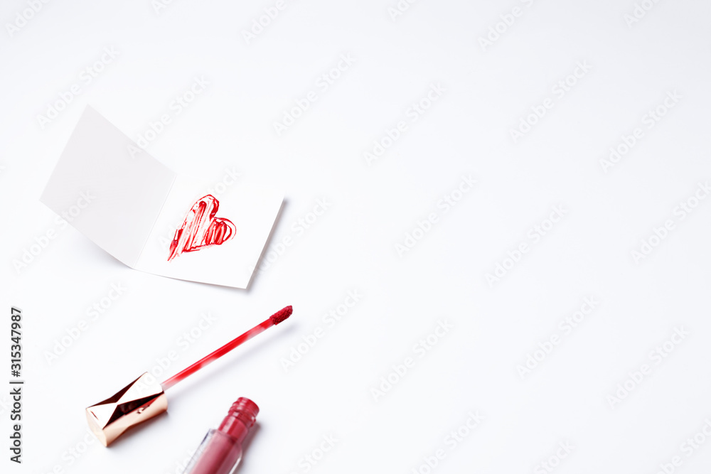 Lipstick-painted red heart on greeting card. Concept of Valentine's Day in beauty industry. Top view, flat lay, copy space for text. Horizontal orientation