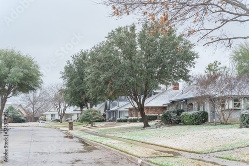 Residential street with bungalow houses under winter snow cover near Dallas