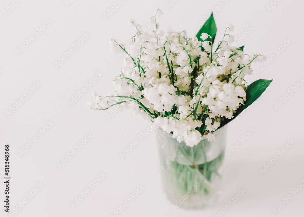 Nice bouquet of lilies of the valley on white background. Concept of holiday, birthday, International Womens Day. Feminine flatlay