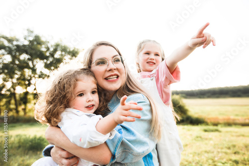 Blonde mother with two cute daughters are walking and having fun outdoors. Stylish  casual clothes.
