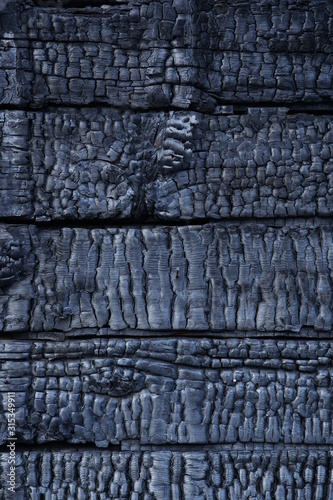 black charcoal background texture of burnt wood. Charred wood planks. Pattern  banner. Vertical photo.