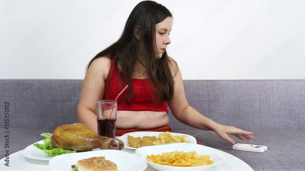 Fat girl with belly eating fried chicken and watching TV. Fat girl with belly eating fried chicken and watching TV.
