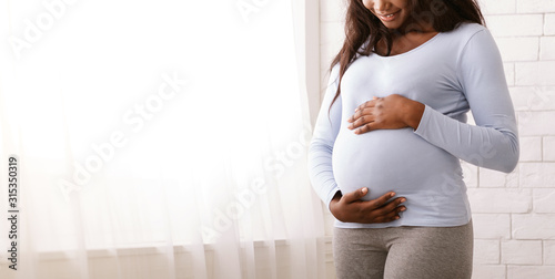 Tablou Canvas Afro woman enjoying her pregnancy, hugging her tummy