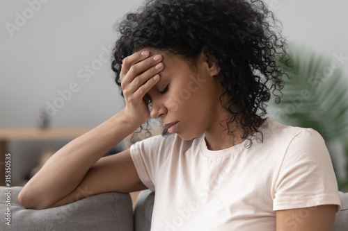 Fotografie African woman sitting on couch feels unhappy having problems