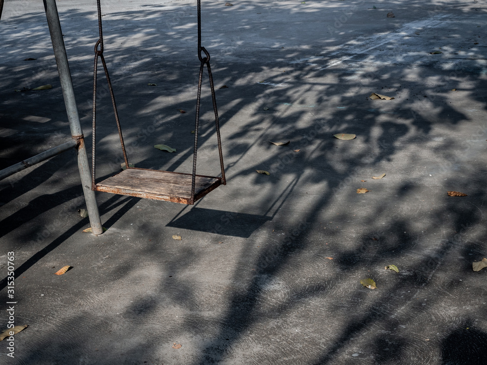 Old lonely wooden swing on sunset time with light and shadow. Old lonely wooden swing on sunset time with light and shadow.