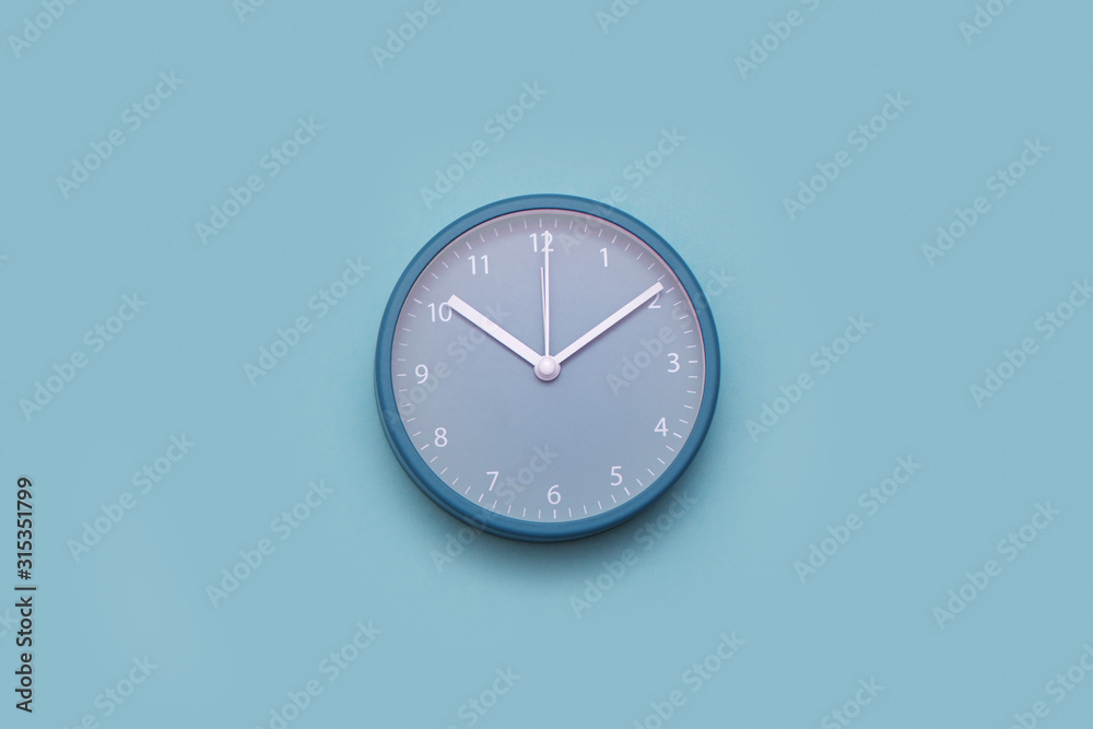 Modern alarm clock on pastel blue background. Minimal concept.
