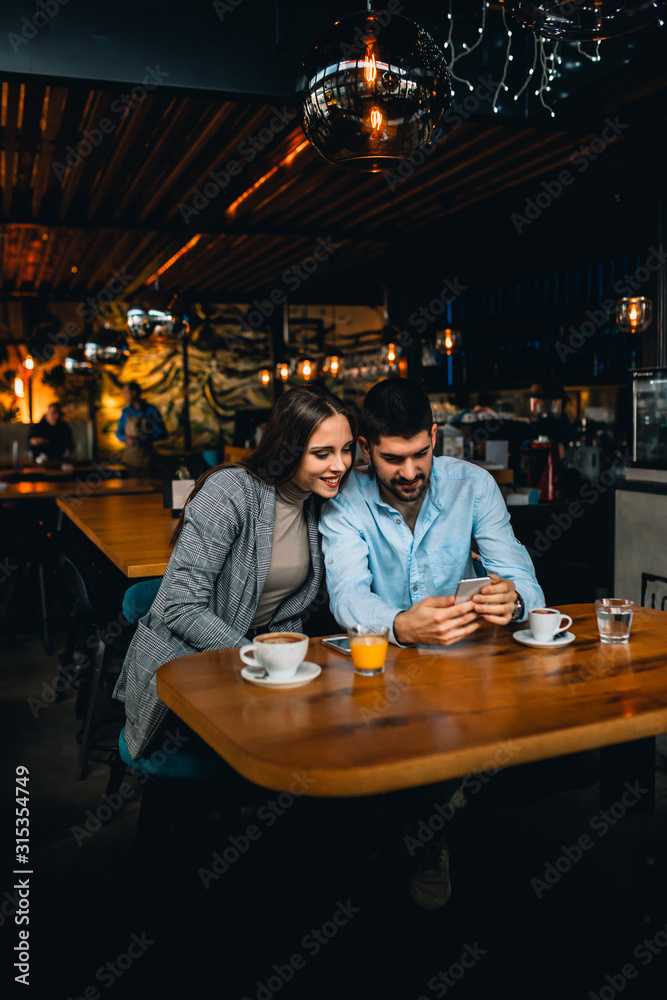 couple using mobile phone while enjoying coffee in cafeteria