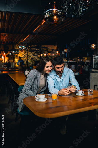 couple using mobile phone while enjoying coffee in cafeteria