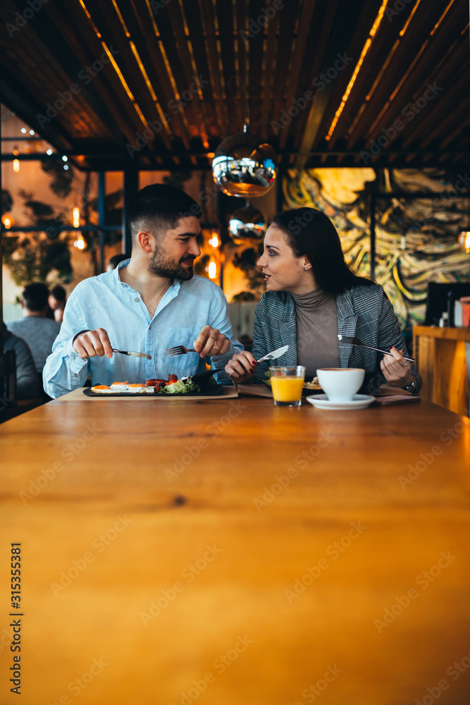 happy couple having breakfast in restaurant or food corner