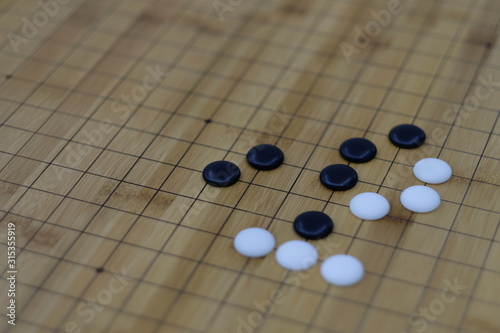close up white and black Go  Weiqi   stones on wooden chessboard. blur background