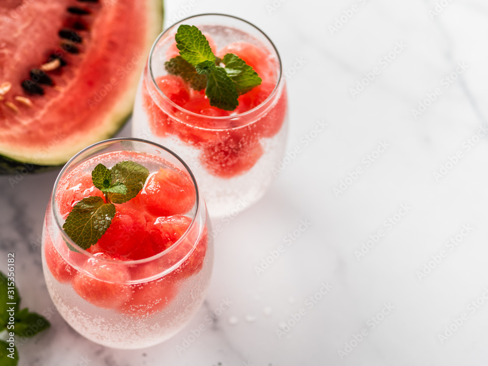 Watermelon ice with sparkling water or soda in glass tumbler. Summer party idea and recipe, add color and flavor for soda or other drink. Copy space. White marble background Watermelon ice with sparkling water or soda in glass tumbler. Summer party idea and recipe, add color and flavor for soda or other drink. Copy space. White marble background