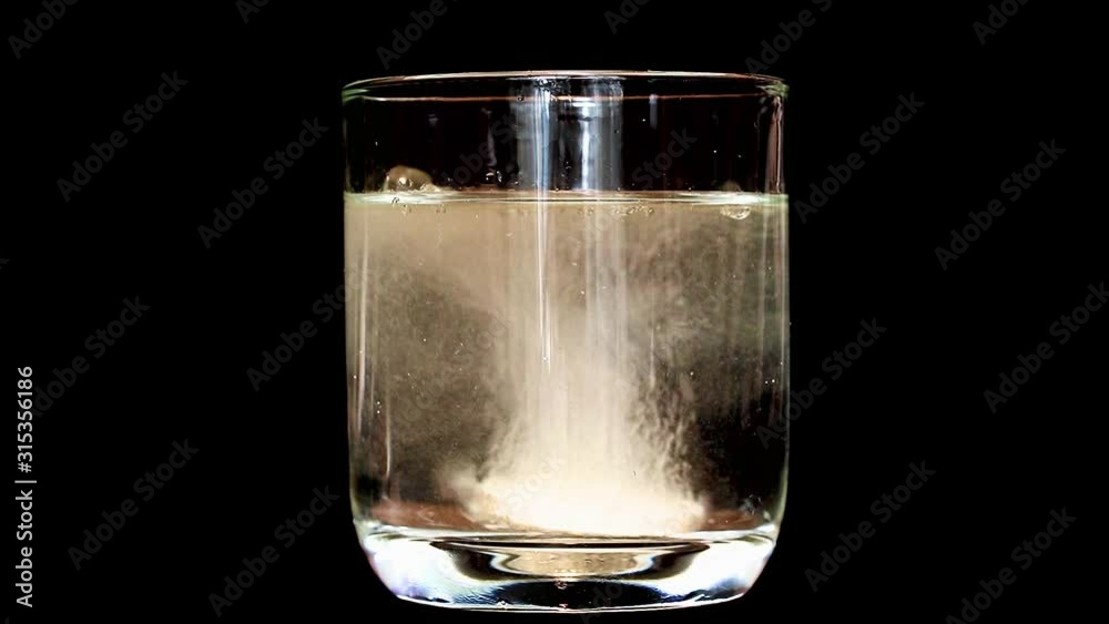 Disolved Glass Tablet dissolve in rotating glass with water, on black background ...