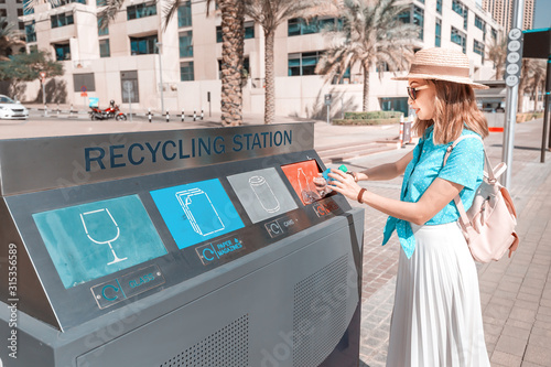 Canvas Print A girl sorts and throws garbage in a street station for recycling plastic waste