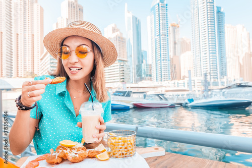 Photography Happy asian woman eats prawns in batter and French fries on the terrace of a sea