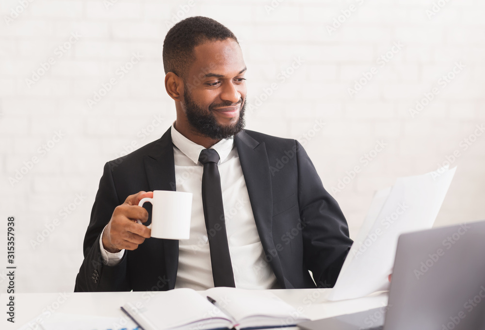 Cheerful businessman drinking coffe, reading daily reports