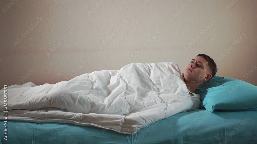 young man wakes up from a nightmare. Continues to sleep on the bed young man wakes up from a nightmare. Continues to sleep on the bed