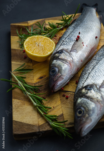 fresh sea bass with lemon and rosemary on a wooden board