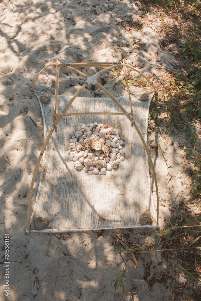 Seashells and dried crab on a hand-made shrimp device on a sandy beach. Seashells and dried crab on a hand-made shrimp device on a sandy beach.