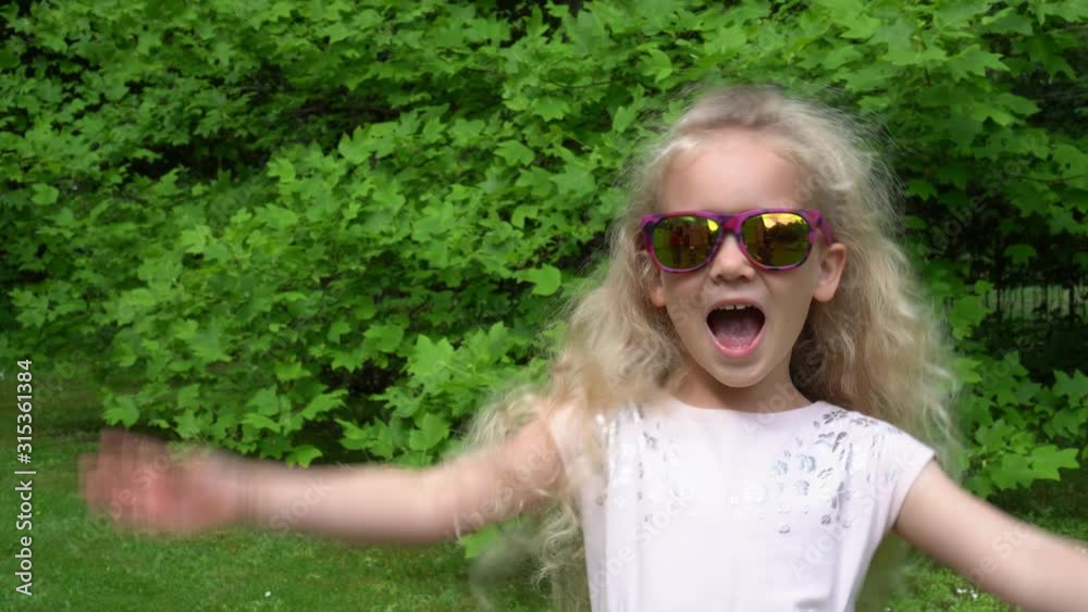 Happy blond girl put sun glasses on. Pretty little lady at park, Gimbal motion. Happy blond girl put sun glasses on. Pretty little lady at park, Gimbal motion.