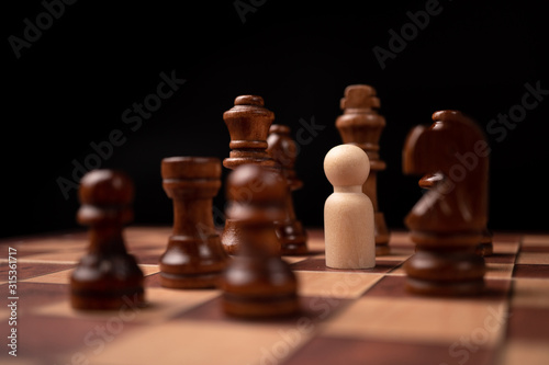 Wooden figures (businessman) standing confront of chess king and being in the chess circle. New business players are facing challenges. The management or leadership, analysis, strategy concept.