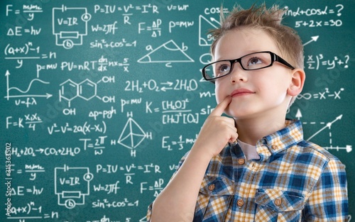 Schoolboy in glasses on blackboard background